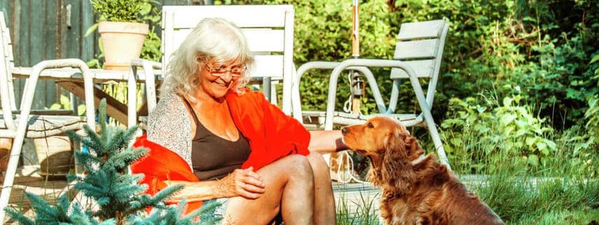 ældre kvinde sidder med sin hund i haven