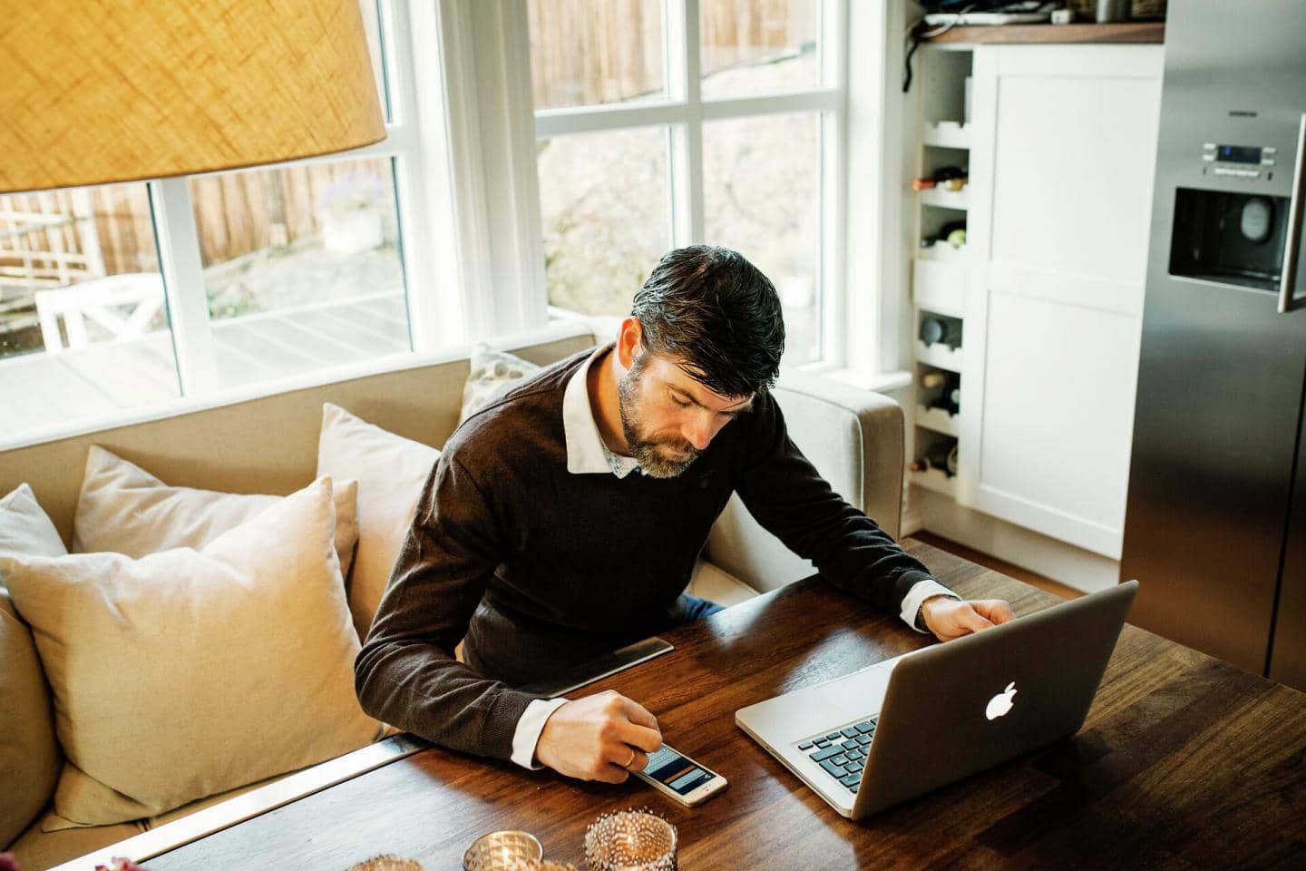 Mand arbejder ved et bord med laptop og smartphone