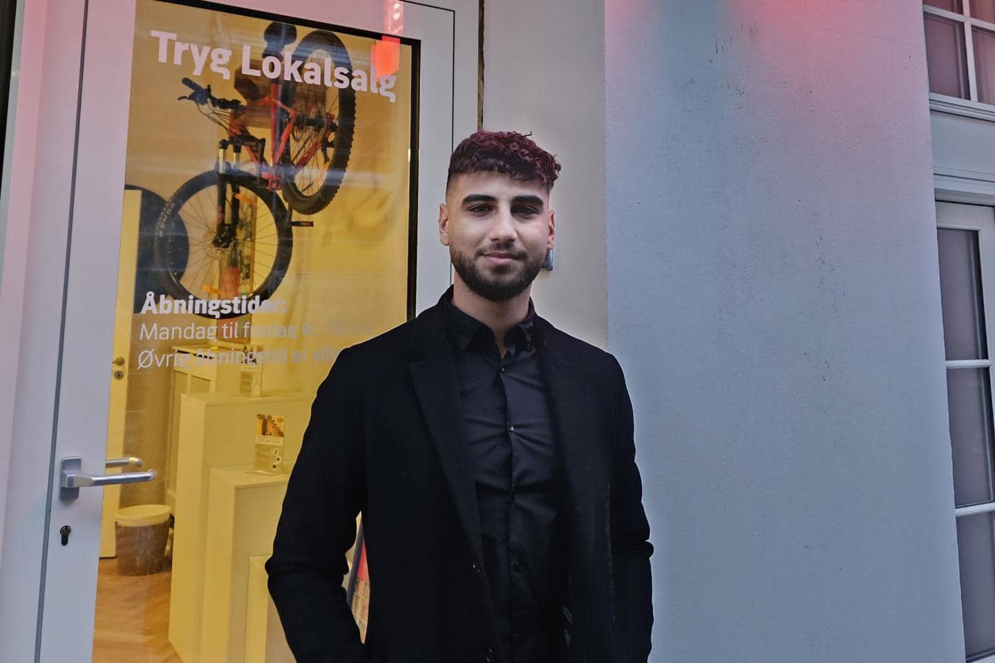 Mand står foran dør og smiler