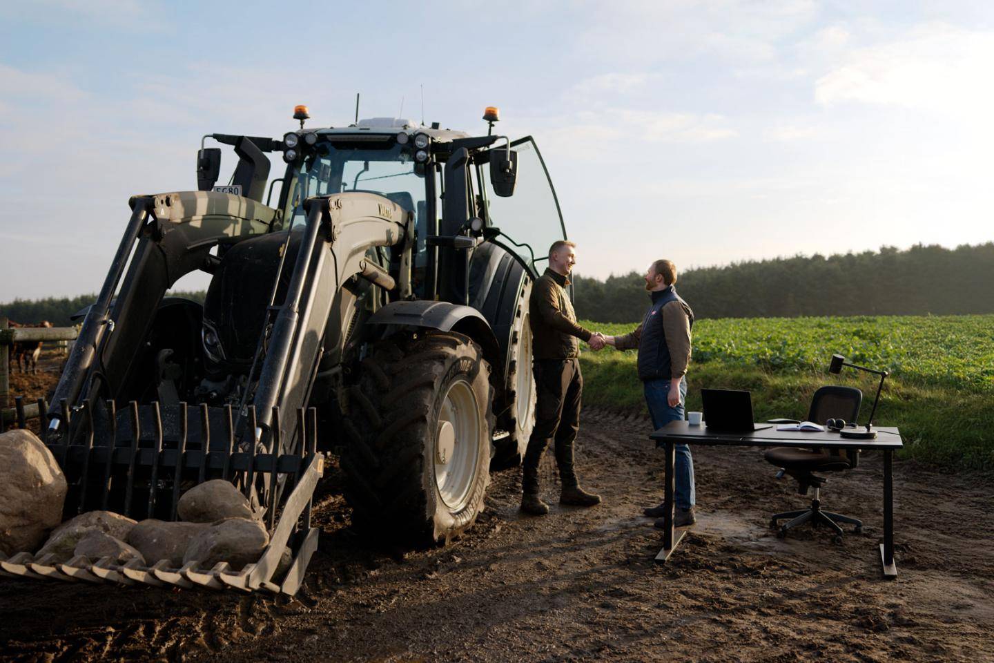 Landmand og landbrugsassurandør giver hånd på en mark