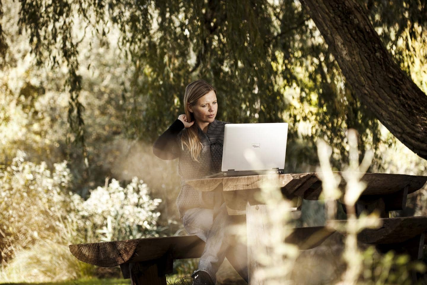 Kvinde sidder i haven og kigger på sin computer